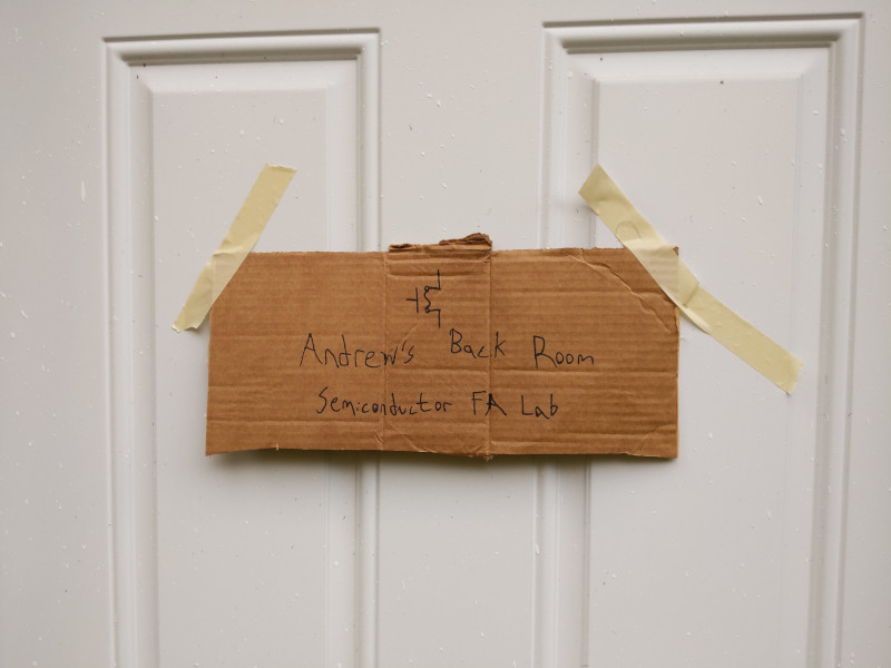 Sign reading 'Andrew's Back Room Semiconductor FA Lab' sharpied on a piece of cardboard taped to a door