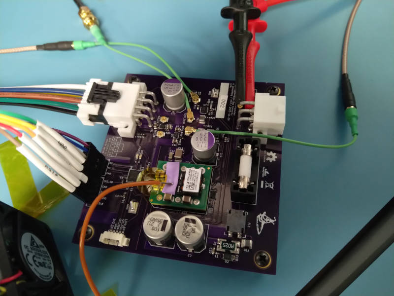 Purple PCB with a bunch of large DC power connectors attached and various test probes hanging off